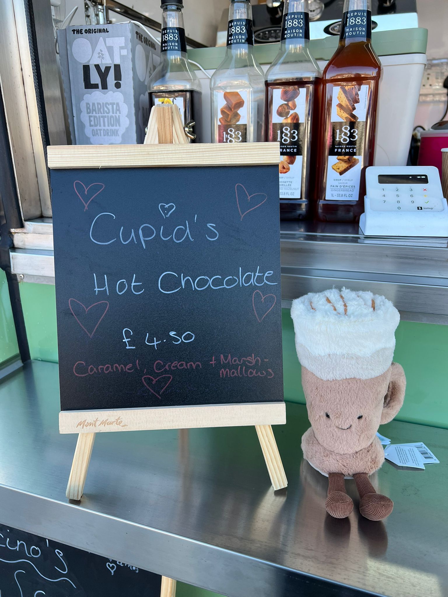 Cupid's Hot Chocolate seasonal special with hearts on the chalkboard and a cute plush