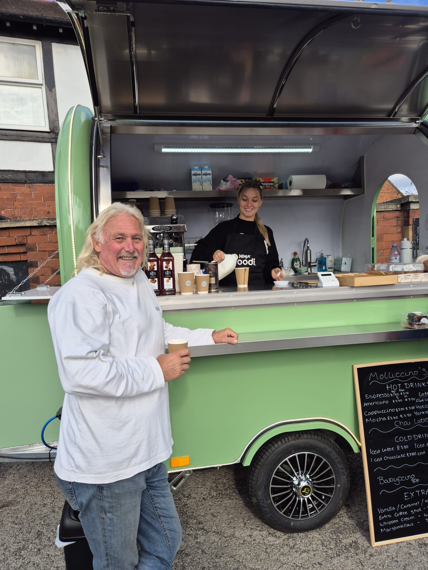 Happy customer smiling and collecting their drink from Molly at the trailer